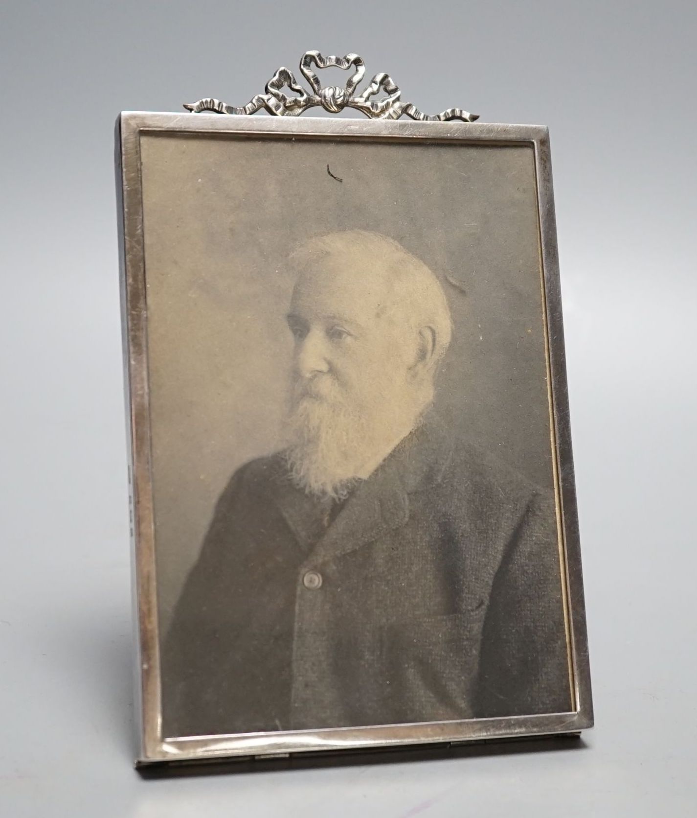An Edwardian silver mounted photograph frame, with ribbon bow crest, Birmingham, 1902, overall 15.8cm.